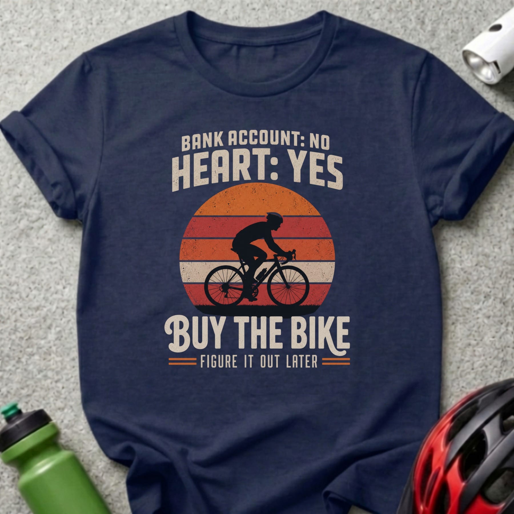 Dark blue t-shirt with graphic of cyclist, sun, and text "Bank account: No heart: Yes. Buy the bike. Figure it out later."