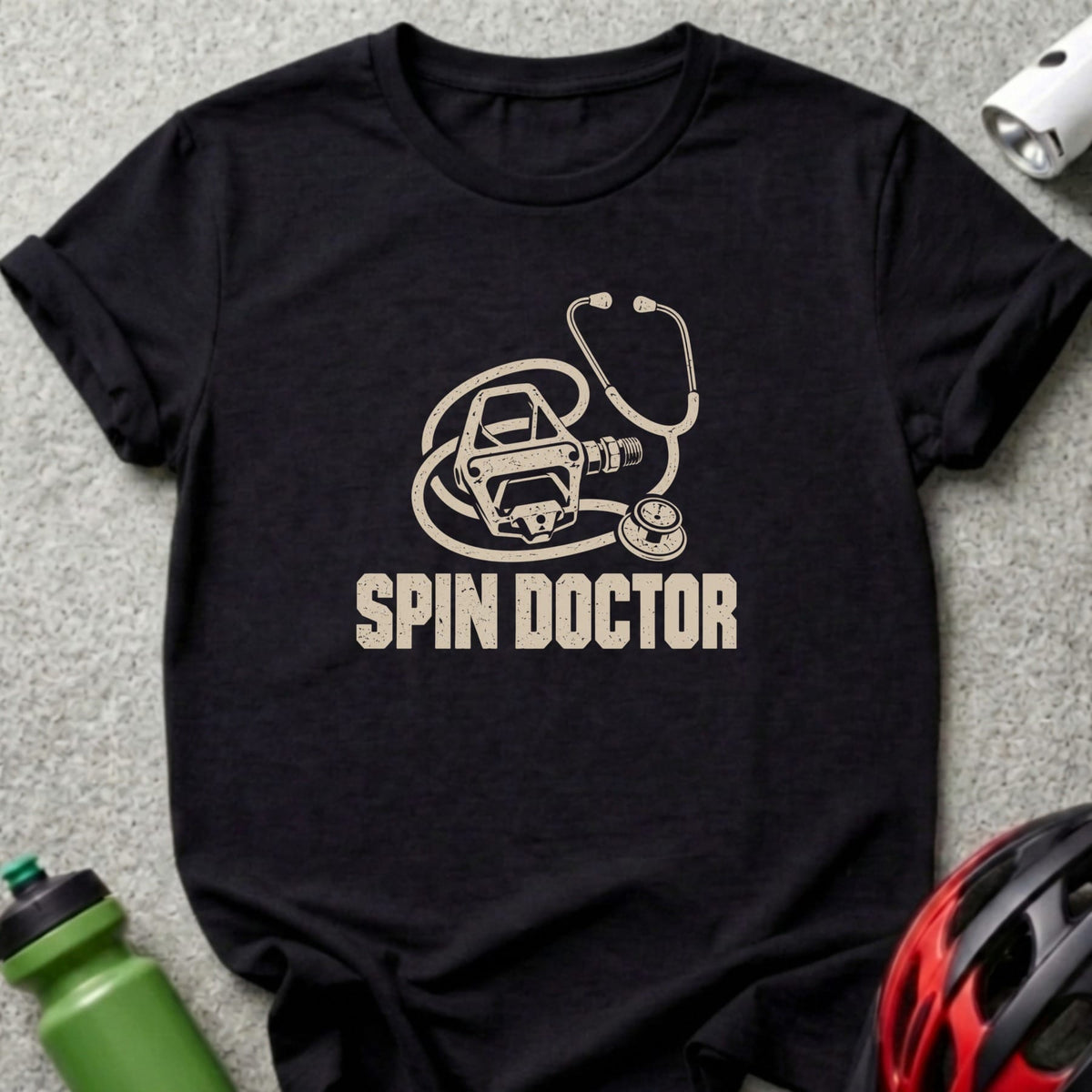 Black t-shirt featuring a beige graphic of a bicycle pedal combined with a stethoscope and the text SPIN DOCTOR.