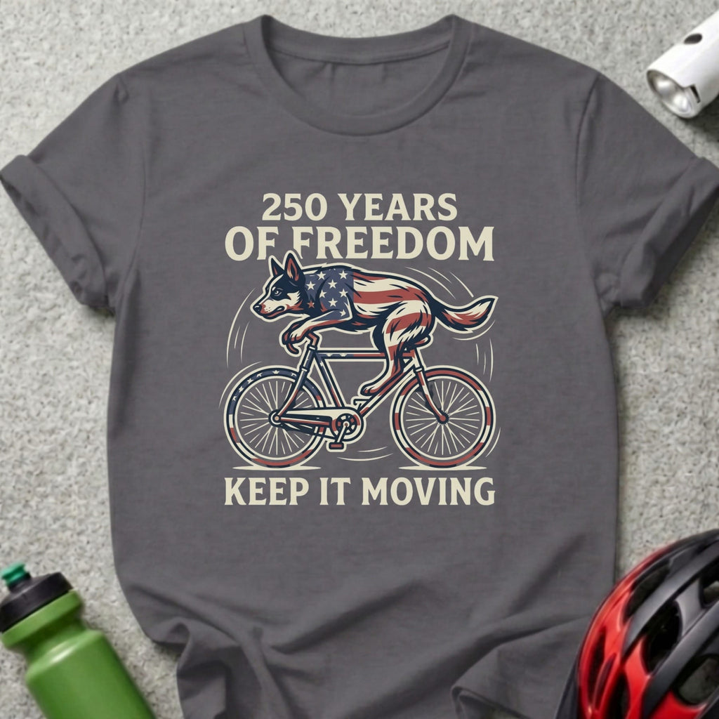 T-shirt with patriotic dog riding a bicycle, text "250 YEARS OF FREEDOM KEEP IT MOVING".