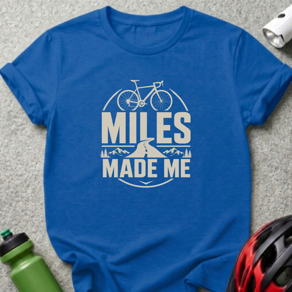 Blue t-shirt with bicycle, road, mountains, and text "MILES MADE ME".