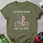 Olive green t-shirt with "250 Years of Freedom Pedal Pint Repeat" and American flag cyclist graphic.