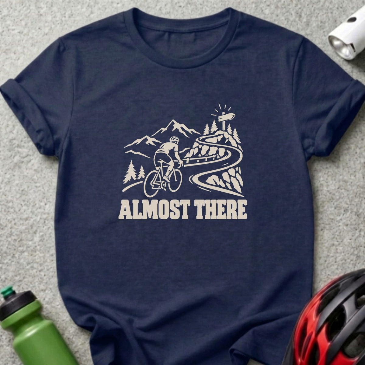 Dark blue t-shirt featuring a white graphic of a cyclist climbing a mountain road with the text ALMOST THERE.