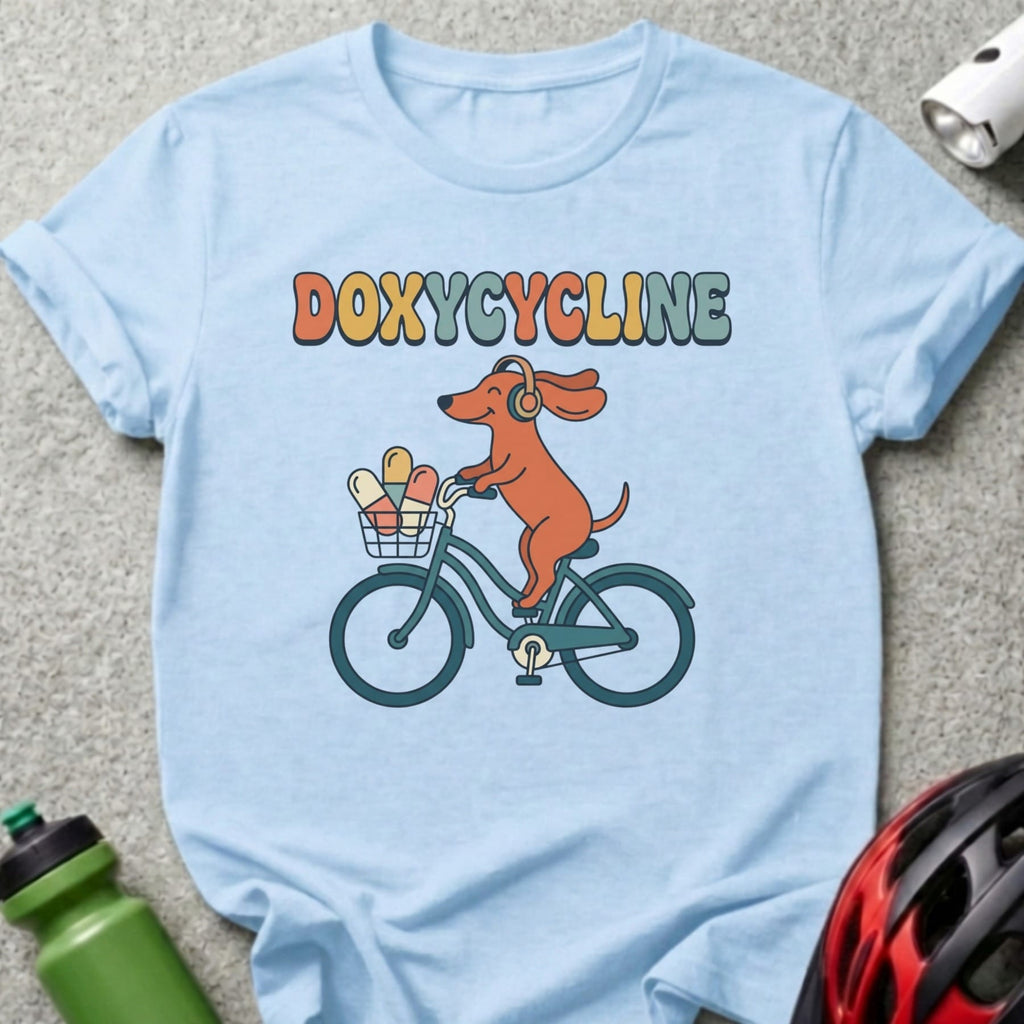 Light blue t-shirt with cartoon dog wearing headphones biking with pills in basket.