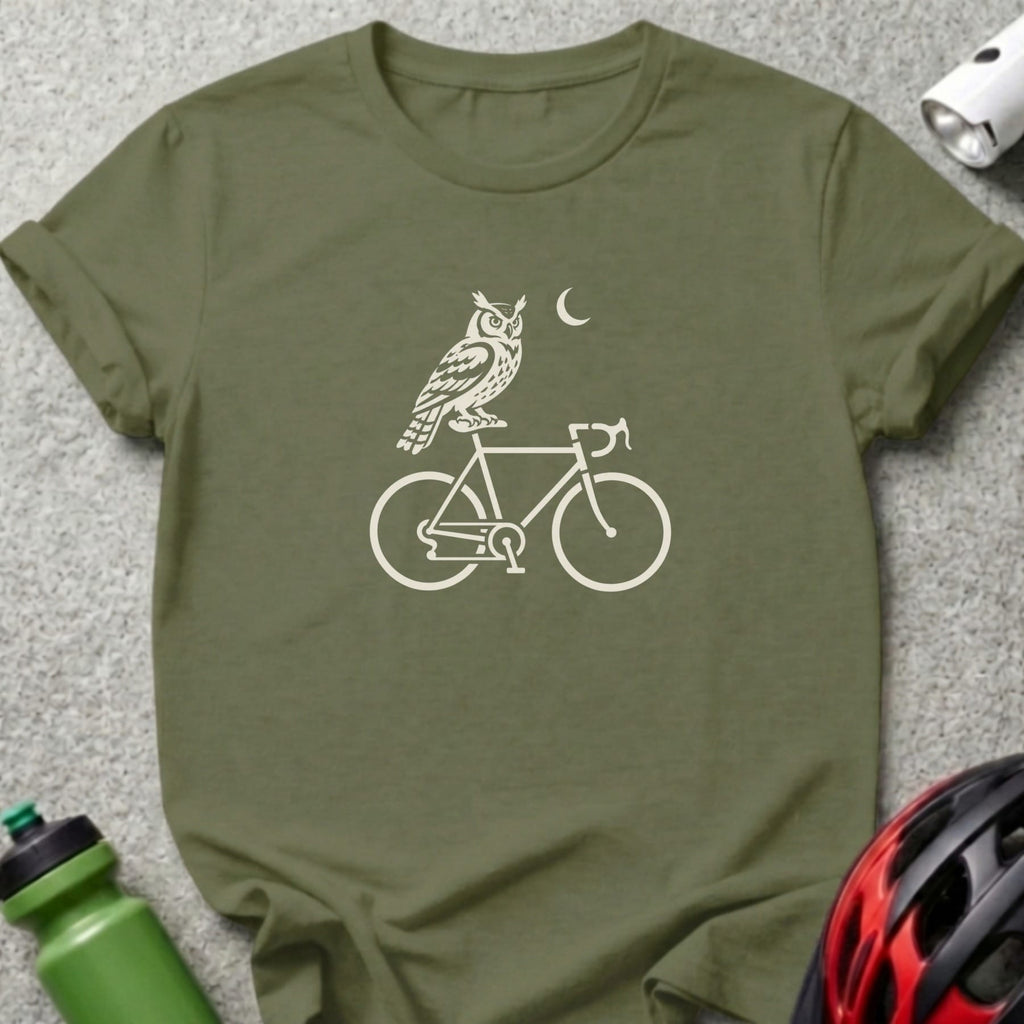 An olive green t-shirt with a white graphic of an owl riding a bicycle beneath a crescent moon.
