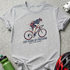 Gray t-shirt with cyclist graphic and text "250 YEARS OF FREEDOM BUILT FOR SPEED".
