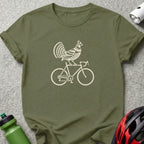An olive green crewneck t-shirt featuring a cream-colored graphic of a turkey riding a bicycle.