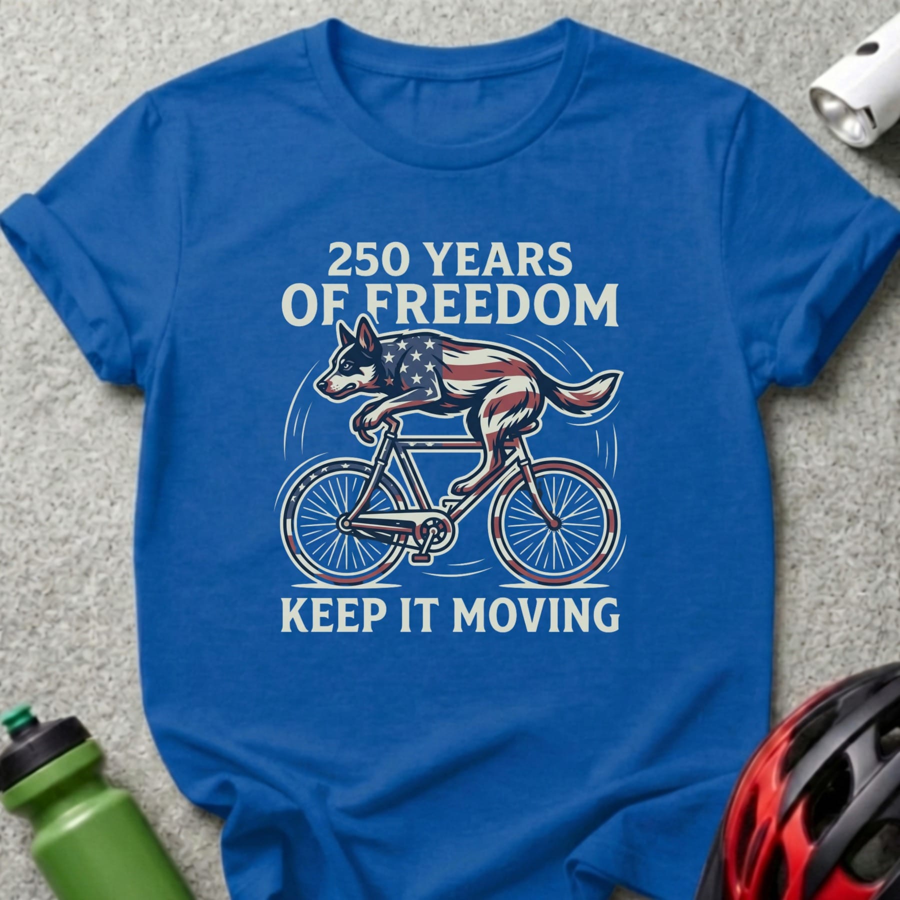 Blue t-shirt with "250 Years of Freedom Keep It Moving" and dog on bike graphic.