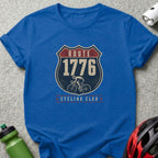Blue t-shirt with "Route 1776 Cycling Club" graphic and cyclist image.