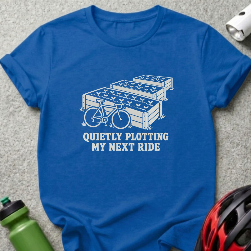 Blue t-shirt featuring a white graphic of raised garden beds, a bicycle, and text reading quietly plotting my next ride.