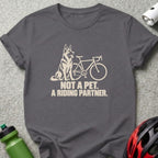 Charcoal t-shirt featuring a cream-colored graphic of a German Shepherd beside a bicycle and text reading, "Not a pet. A riding partner."
