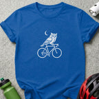 Blue t-shirt with white graphic of owl riding a bicycle under a moon.