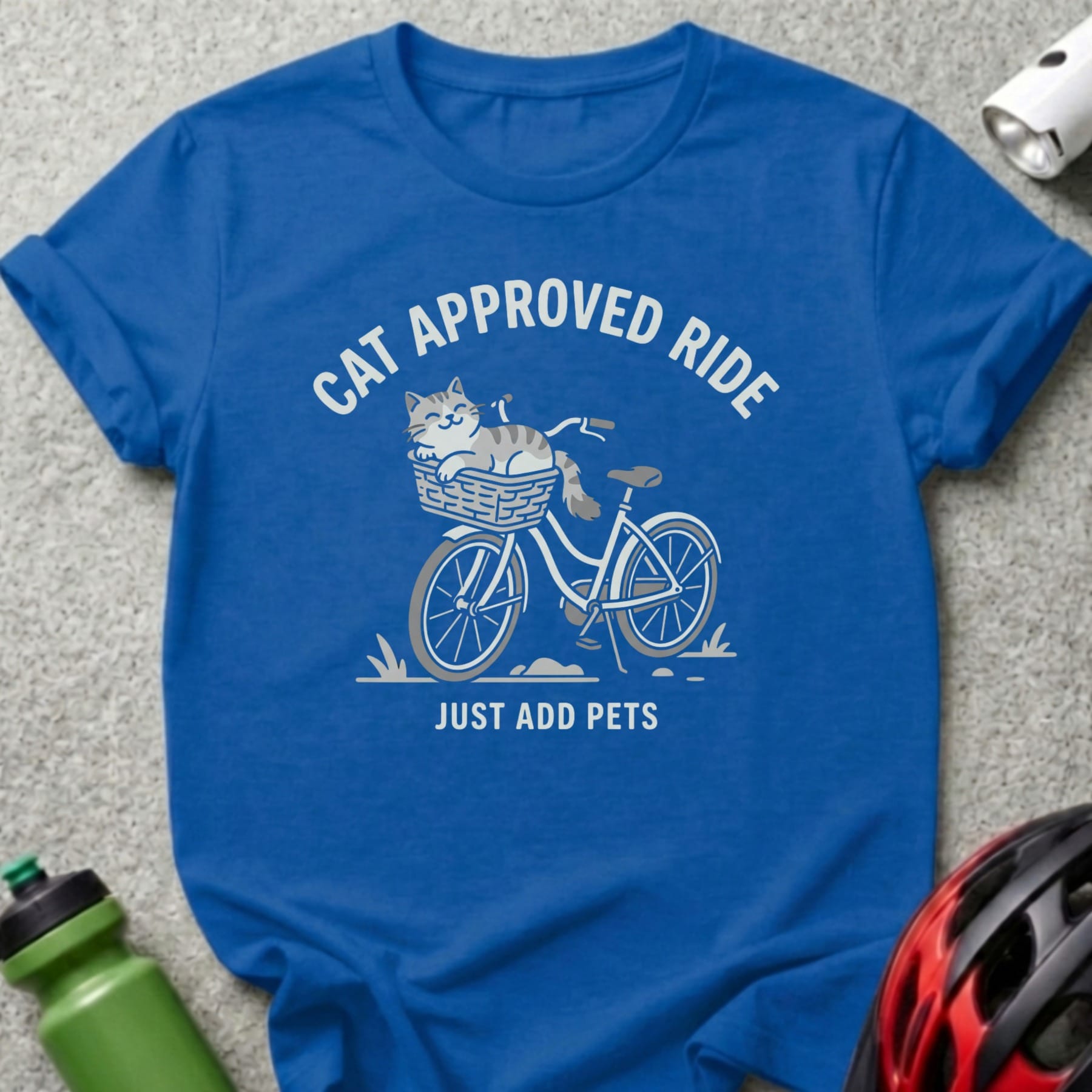 Blue t-shirt with a cat in a basket on a bicycle, text "CAT APPROVED RIDE JUST ADD PETS".