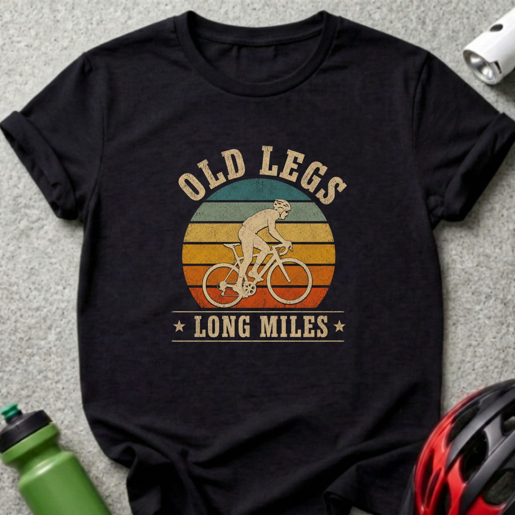 T-shirt with cyclist silhouette, "OLD LEGS LONG MILES" text, and vintage sunset graphic.