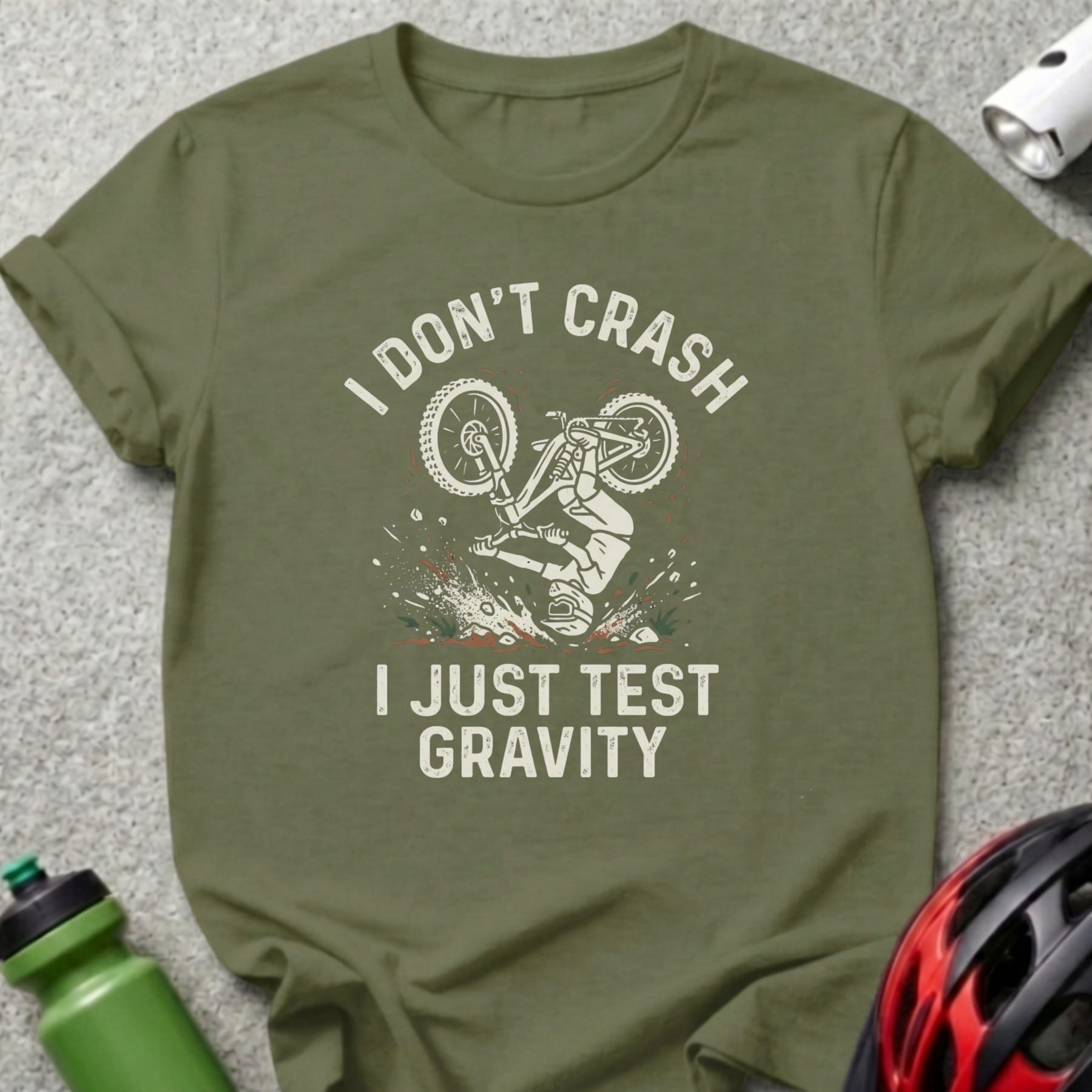 Olive green t-shirt with "I don't crash I just test gravity" and biker graphic.