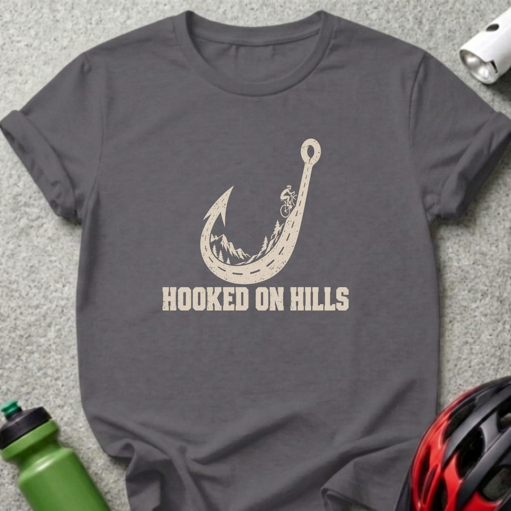 Dark gray t-shirt featuring a fishing hook shaped like a mountain road, with text reading HOOKED ON HILLS.