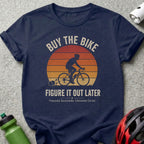 Navy t-shirt with "BUY THE BIKE FIGURE IT OUT LATER" text and a cyclist at sunset graphic.