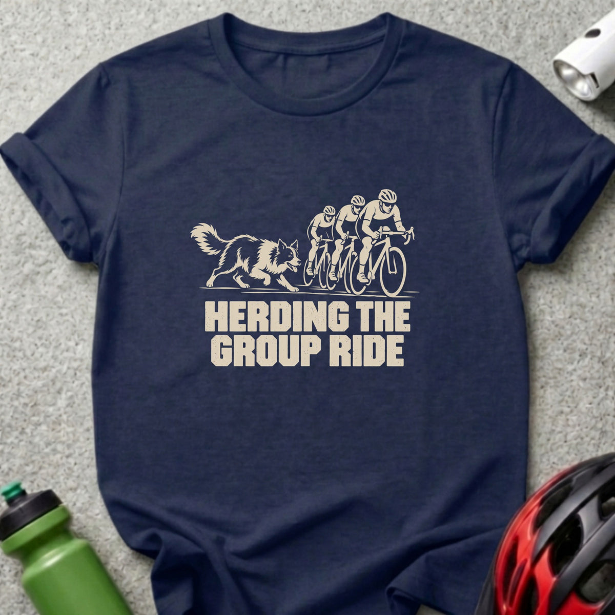 A dark blue t-shirt printed with a graphic of a dog herding three cyclists and text reading "Herding the Group Ride".