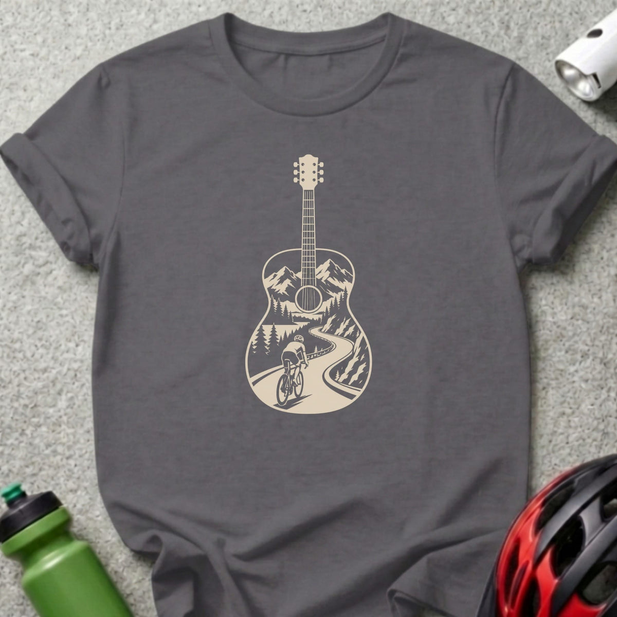 A dark gray t-shirt with a cream-colored graphic of a guitar silhouette enclosing a mountain cycling scene.