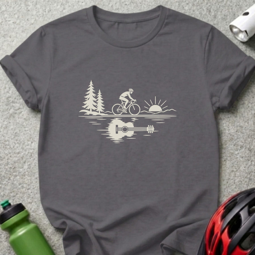 A dark gray t-shirt featuring a white graphic of a cyclist, trees, sun, and an acoustic guitar reflection.