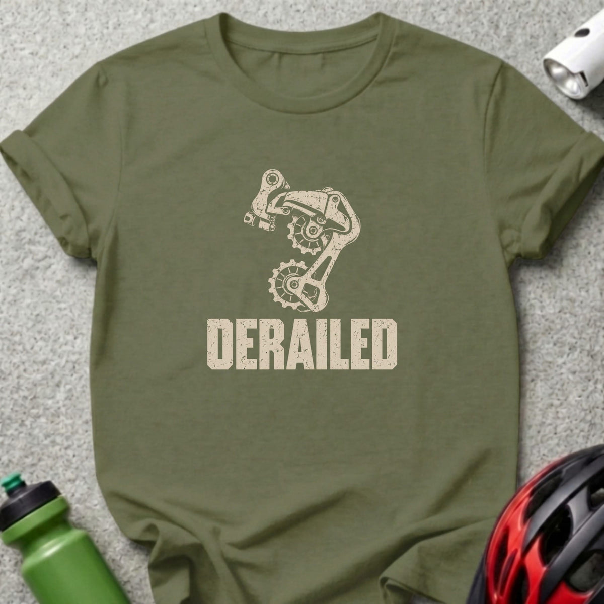 An olive green t-shirt with a distressed graphic of a bicycle derailleur and the word Derailed.