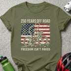 Olive green t-shirt with cyclist silhouette on American flag, reads "250 YEARS OFF ROAD FREEDOM ISN'T PAVED".
