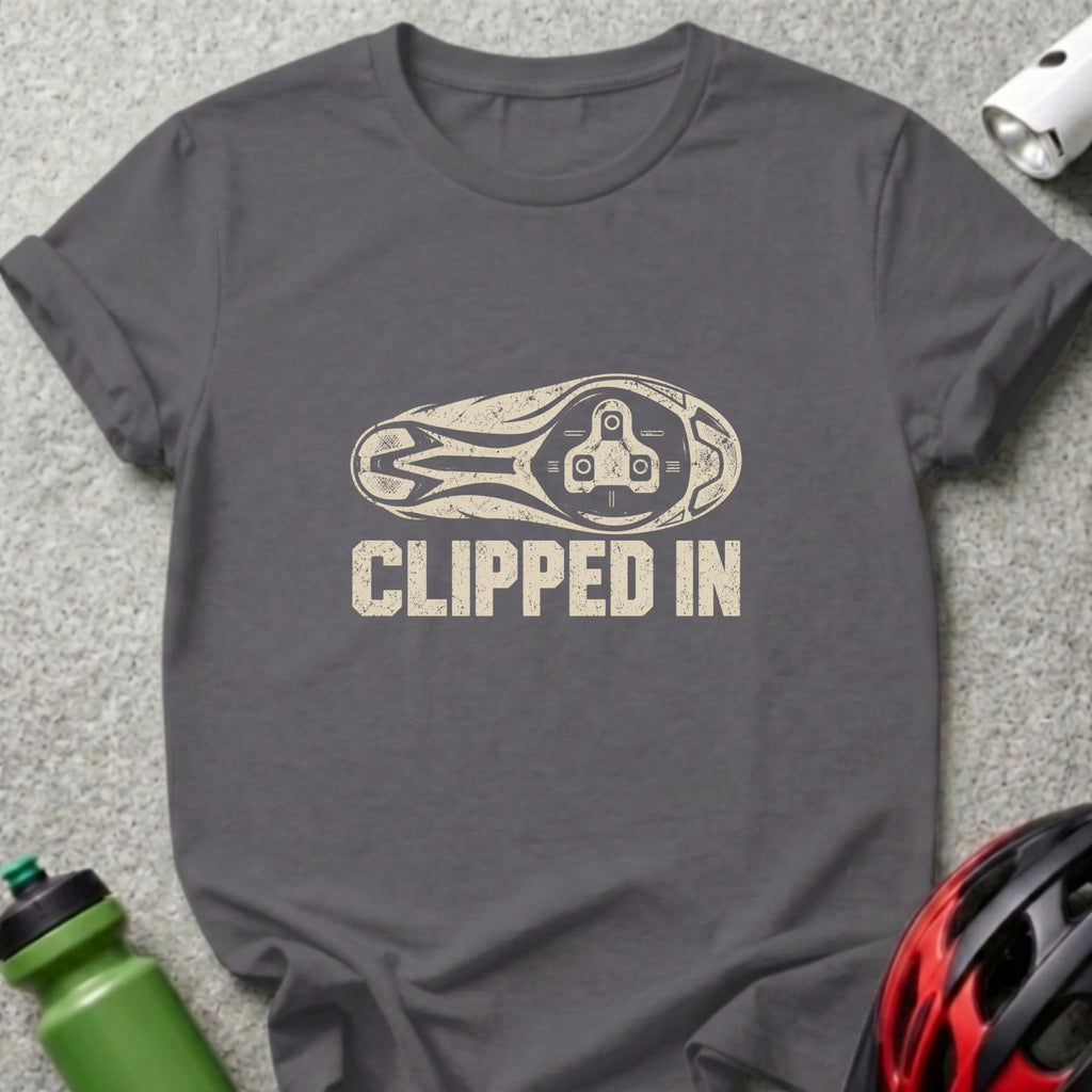 A charcoal gray t-shirt with a distressed graphic of a bicycle cleat and the text CLIPPED IN.