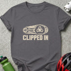 A charcoal gray t-shirt with a distressed graphic of a bicycle cleat and the text CLIPPED IN.
