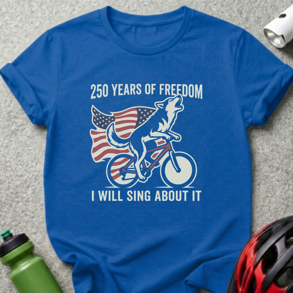 Blue t-shirt with wolf on bicycle and American flag, text "250 Years of Freedom I Will Sing About It".