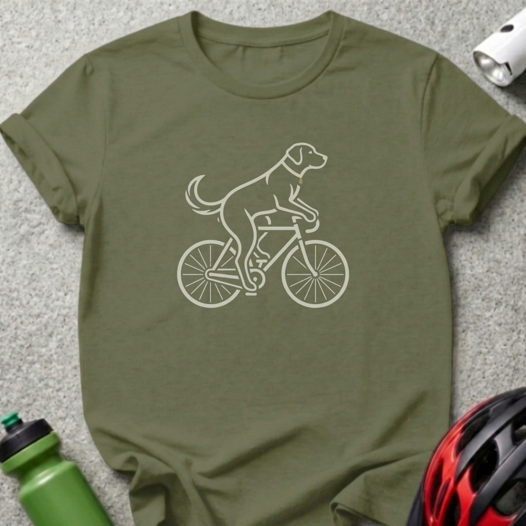 Line art of a dog riding a bicycle on an olive green t-shirt.
