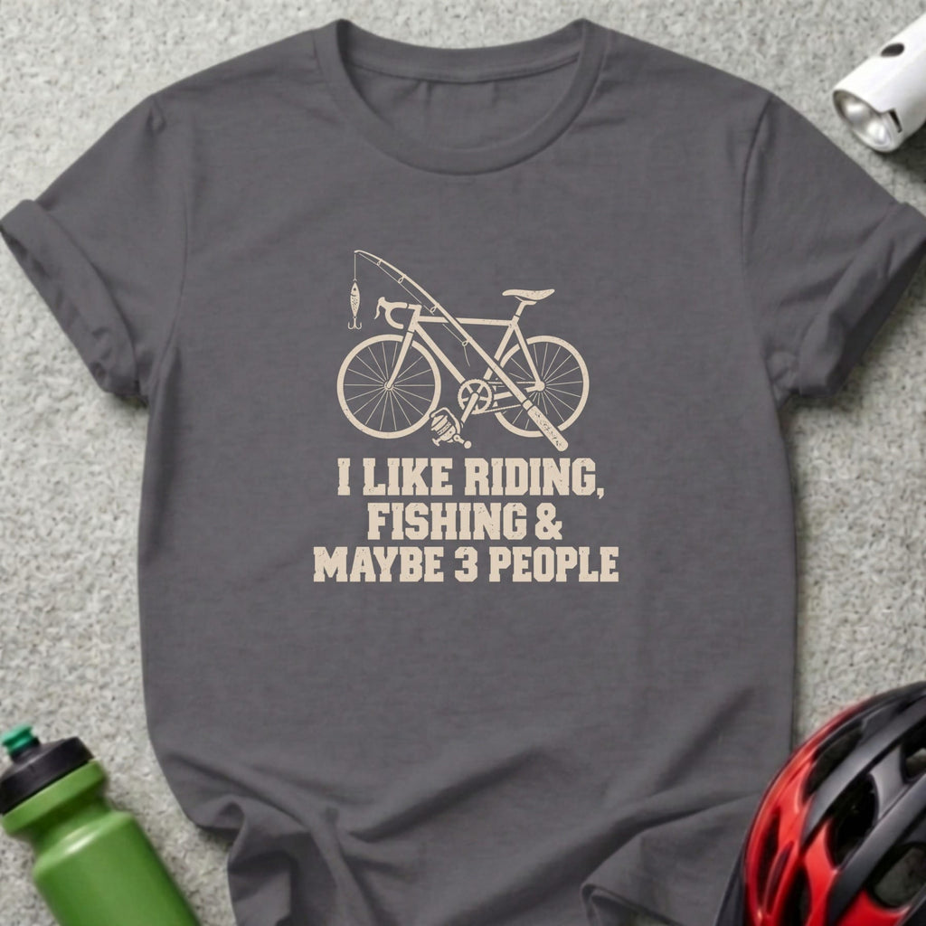 A dark grey crewneck t-shirt featuring a graphic of a bicycle with a fishing rod and the text I LIKE RIDING, FISHING AND MAYBE 3 PEOPLE.