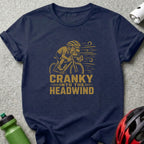 Dark blue t-shirt with graphic art of a cranky cyclist and text "CRANKY INTO THE HEADWIND".