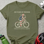 Olive green t-shirt with patriotic cyclist graphic and text "250 Years of Freedom Fueled by Coffee & Liberty".