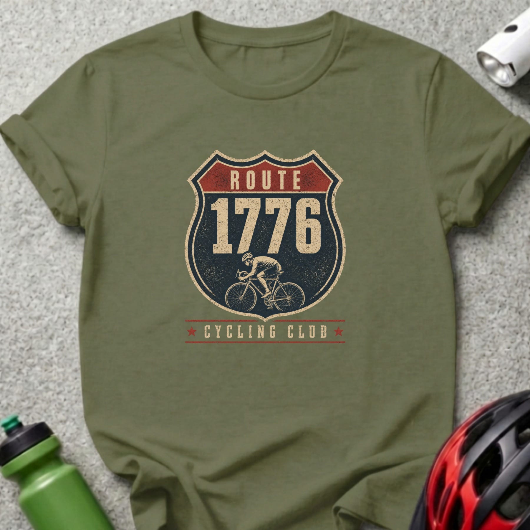 Olive green t-shirt with "Route 1776 Cycling Club" shield logo and cyclist graphic.
