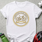 White t-shirt with a gold circular graphic of a bicycle and text "Certified Gear Addict".
