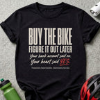 Black t-shirt with text: "BUY THE BIKE FIGURE IT OUT LATER Your bank account said no. Your heart said YES. Financially Questionable. Emotionally Correct."