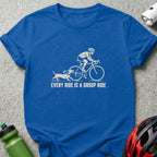 A royal blue t-shirt printed with a white graphic of a cyclist and a dachshund, accompanied by the text "EVERY RIDE IS A GROUP RIDE".