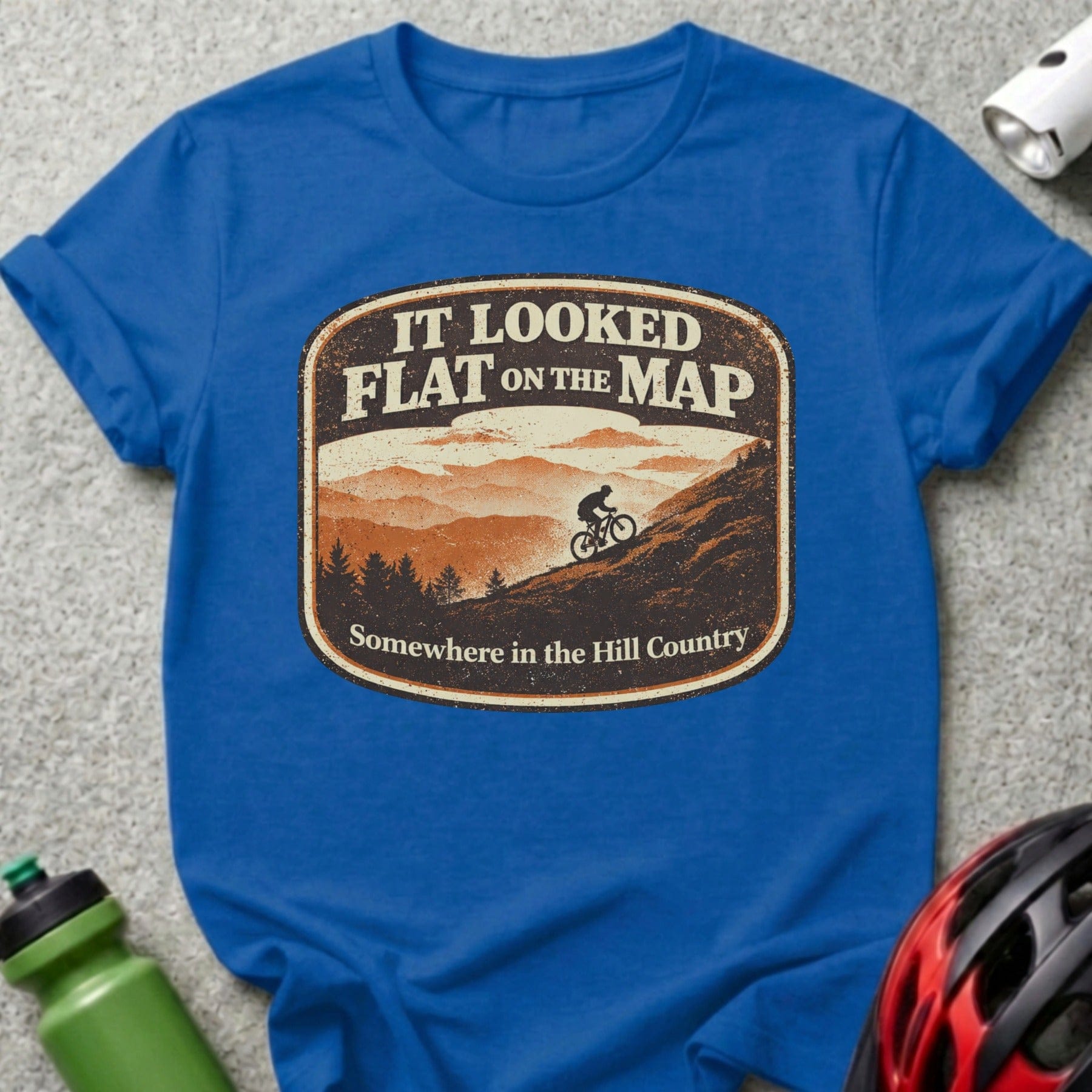 T-shirt with "It Looked Flat on the Map" graphic of cyclist in hills.